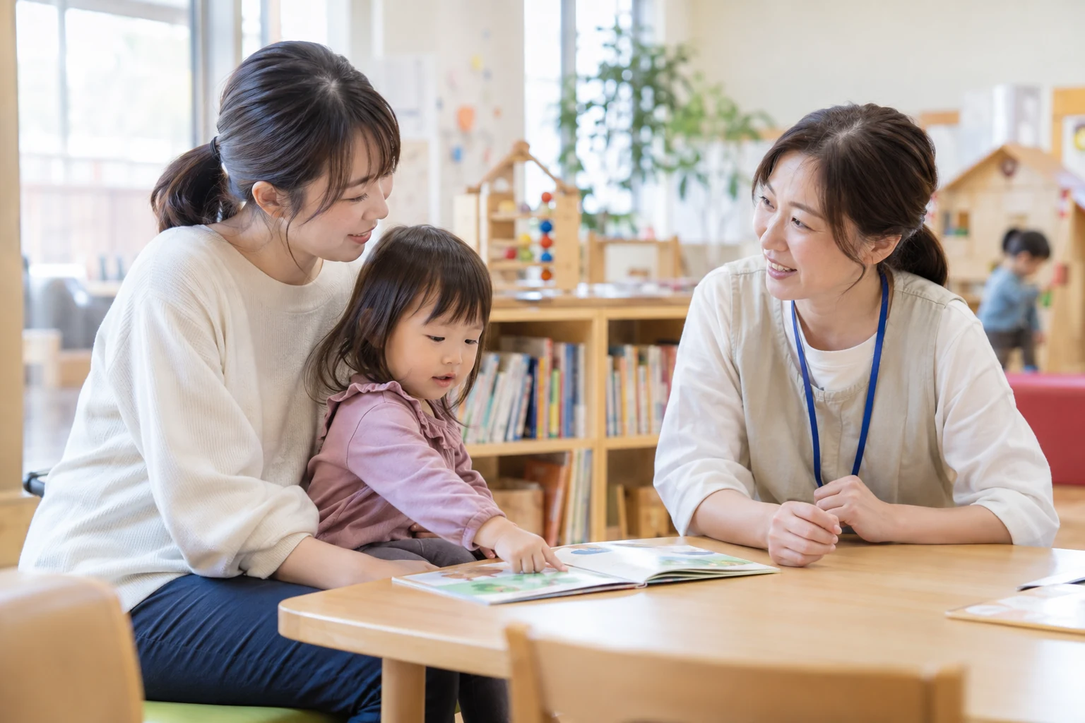 子育て支援施設で親子と相談員が絵本を囲んで話している様子